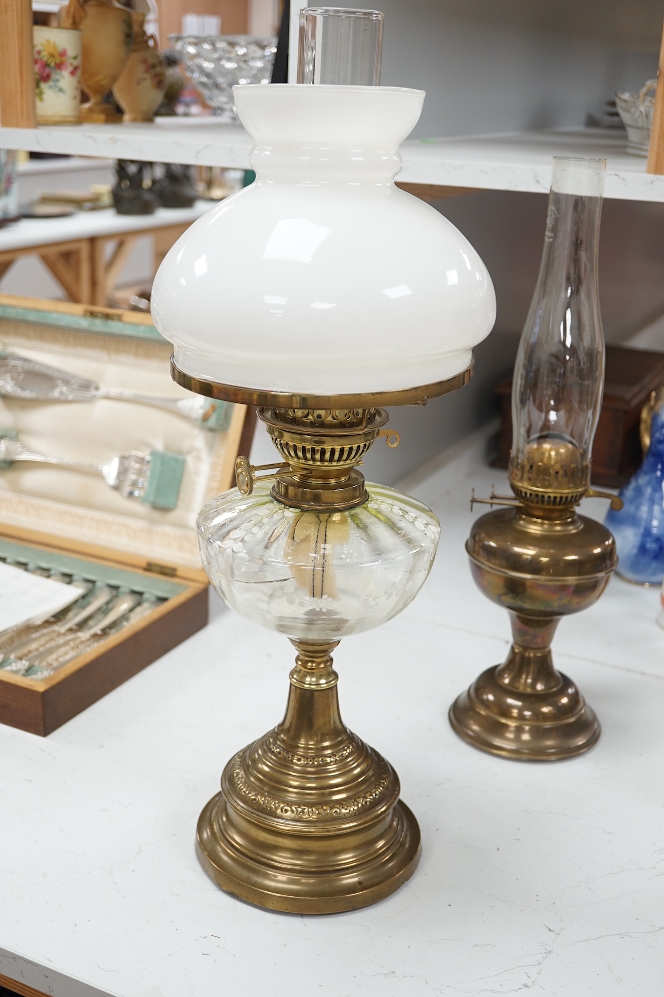 A late 19th century brass oil lamp with painted bowl and opaque shade together with a later oil lamp, largest 59cm high. Condition - fair to good